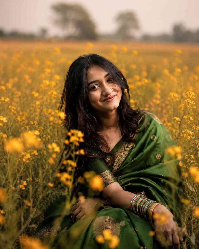 Young Indian woman in a green silk saree sitting in a mustard flower field in Bihar during golden hour AI photo editing prompt